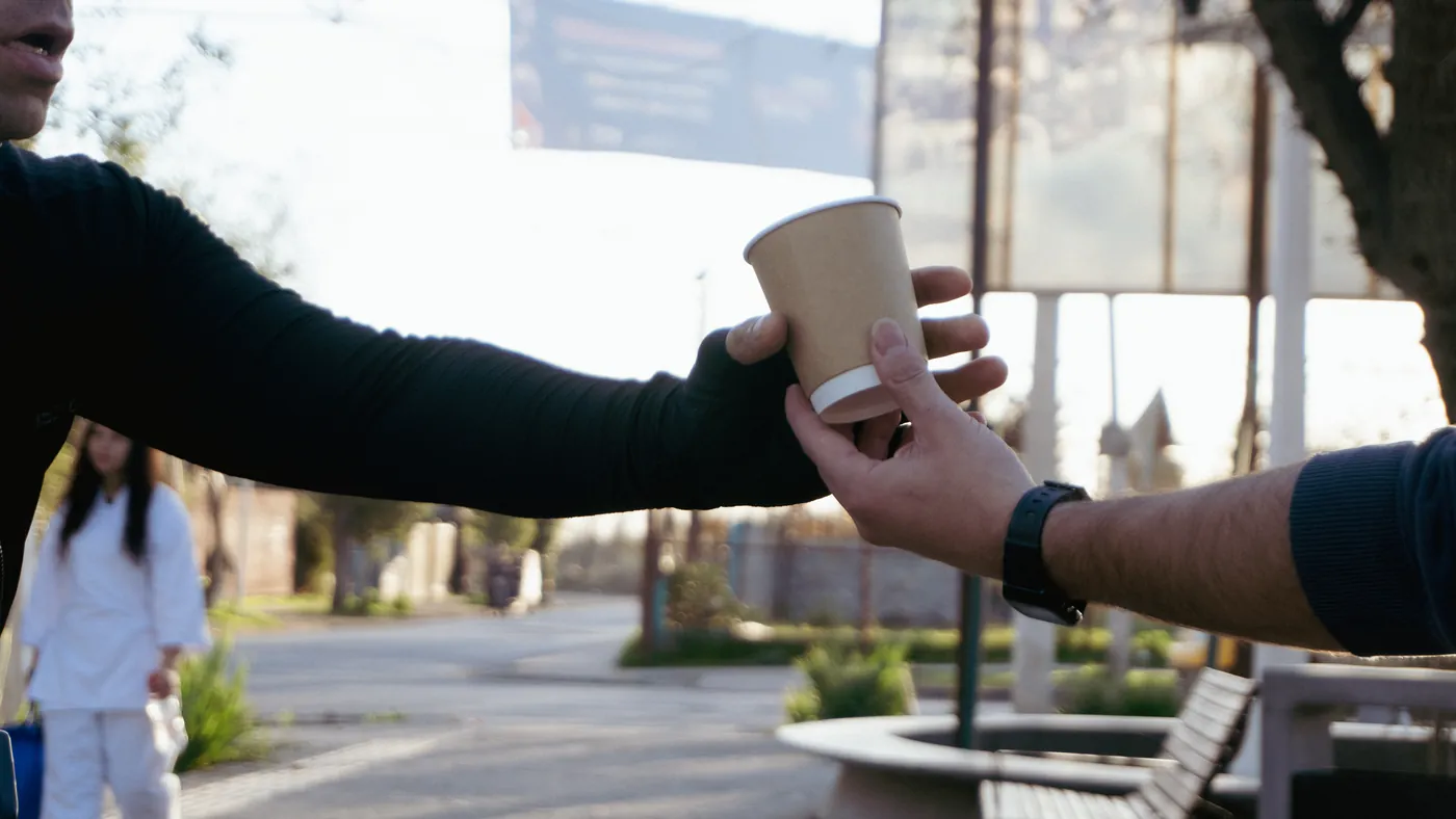 El café pasando de una mano a otra en la calle, recién entregado.
