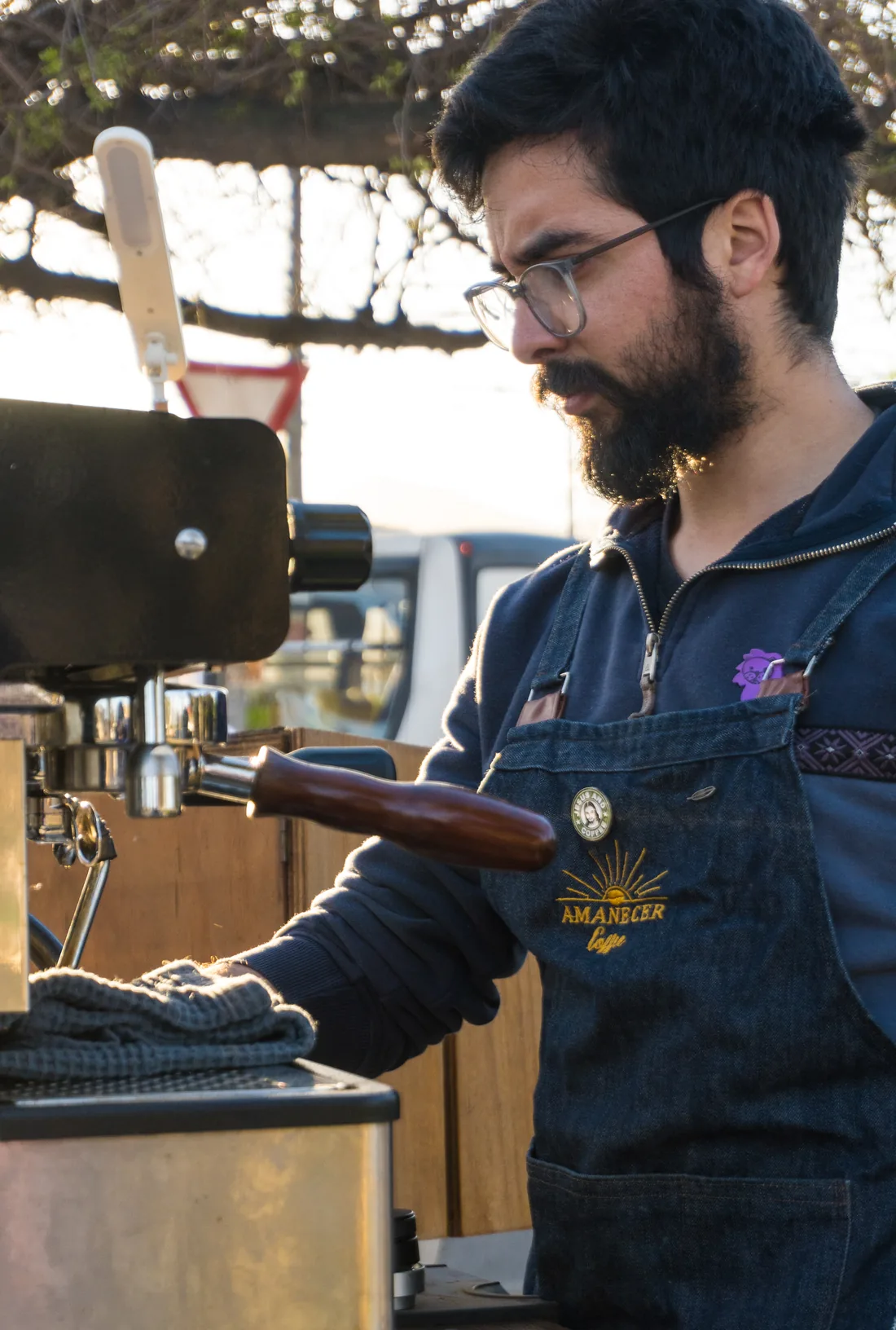 Matías prepara un café mirando la máquina de espresso montada en el triciclo.