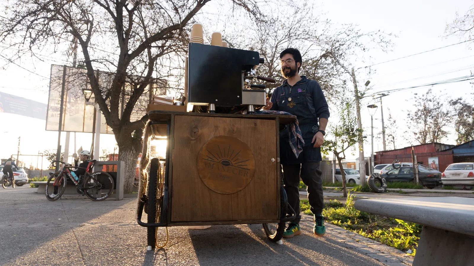 Vista frontal del triciclo cafetería con la máquina y el molino montados sobre el mesón de madera.